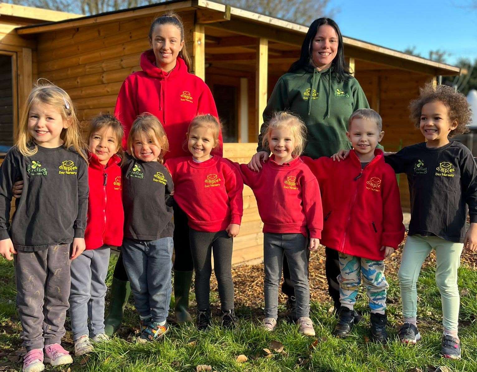 Dimples Day Nursery children and staff outside the forest school cabin